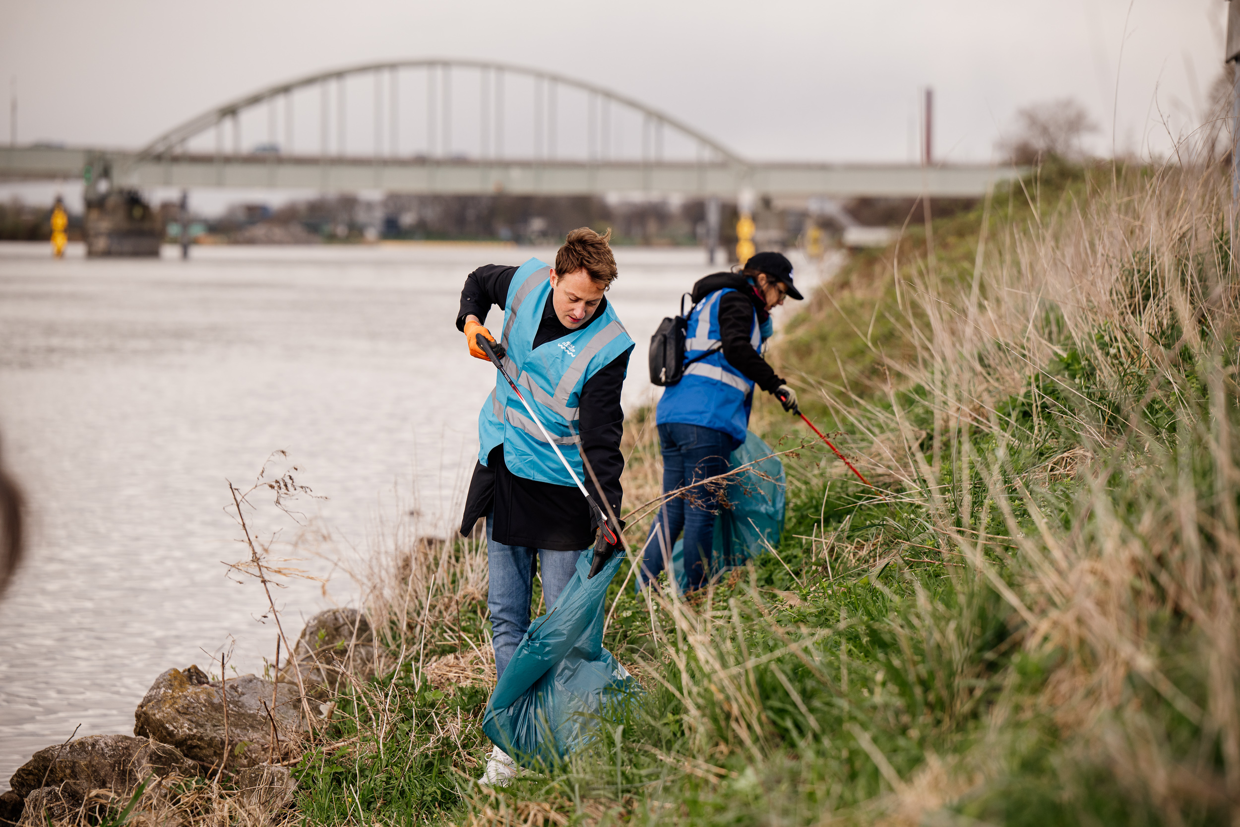 2 personen afval aan het opruimen langs de maas.