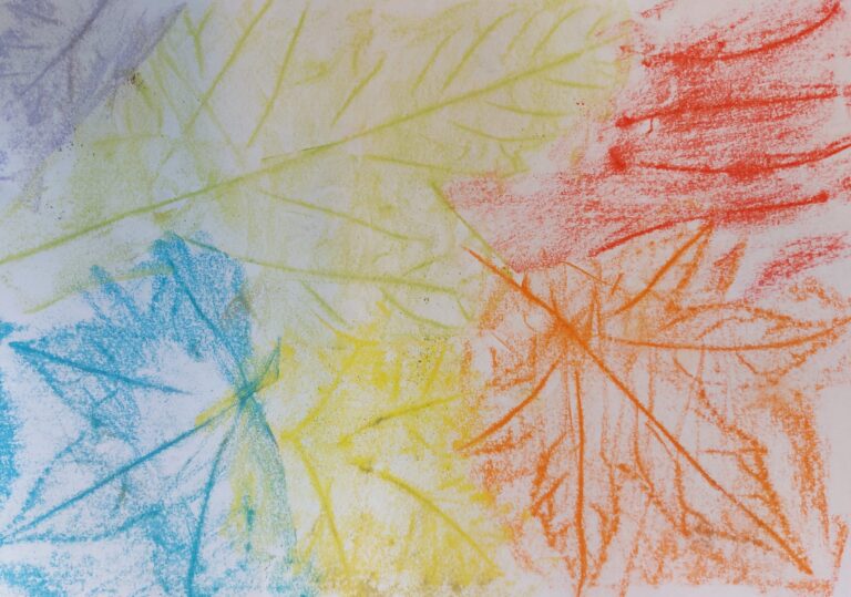 Kleurige krijttekening van bladeren in blauw, geel, groen en oranje op wit papier.