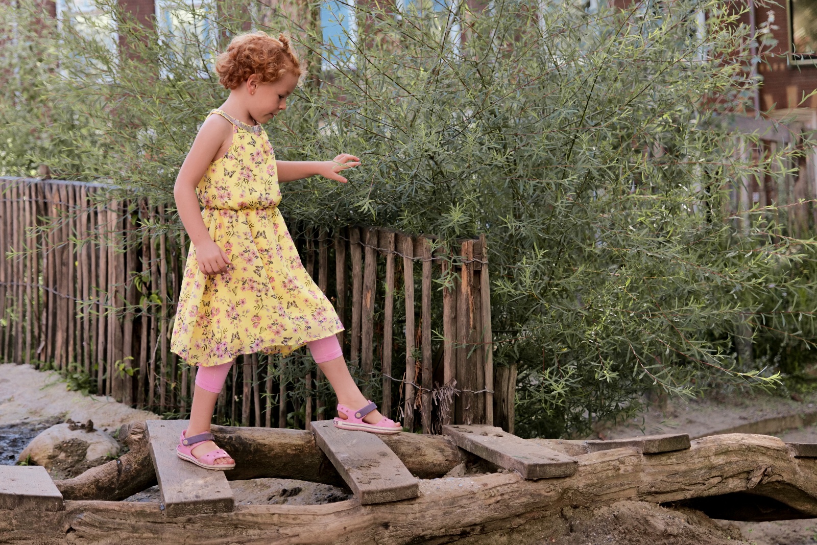 Meisje loopt over houten brug op groen schoolplein