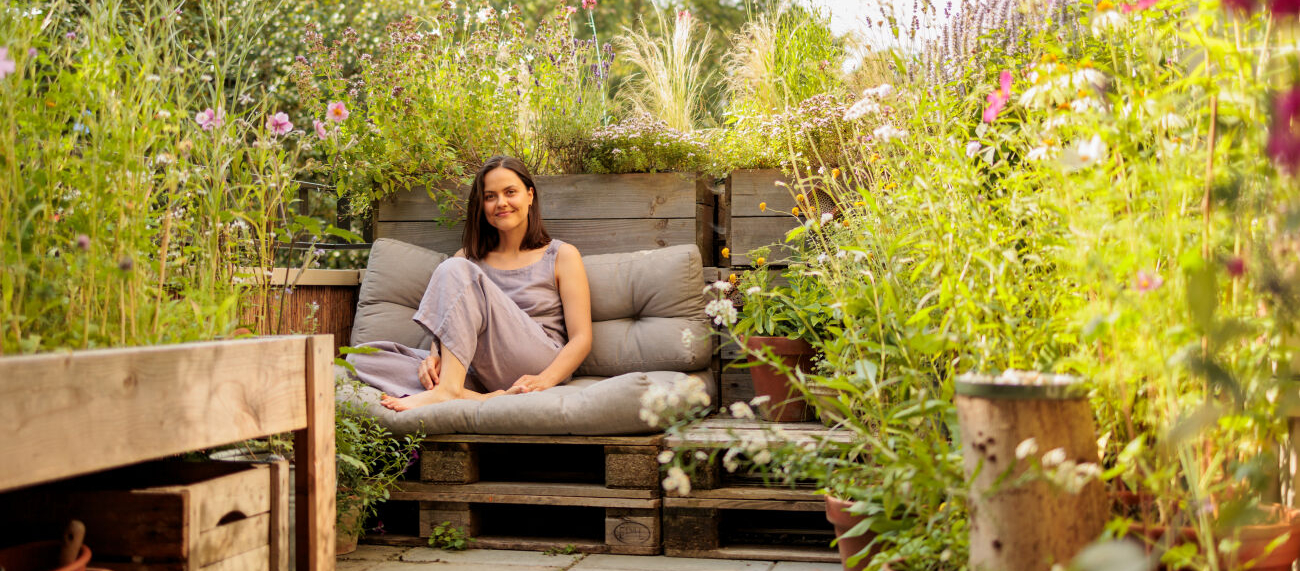 vrouw op loungebank omringd door groen