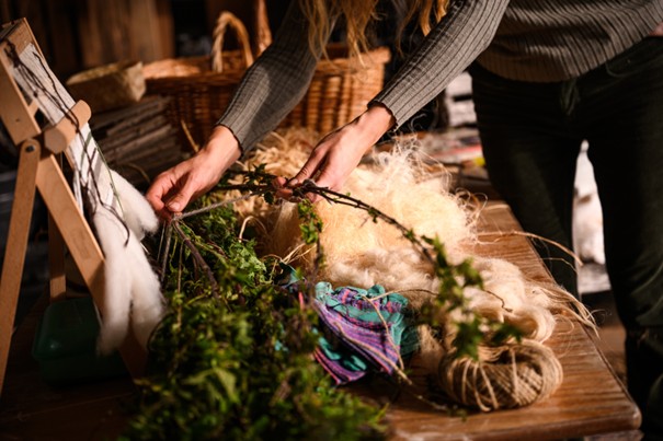 Handen rangschikken takken en touw op een tafel met wol en een mand.