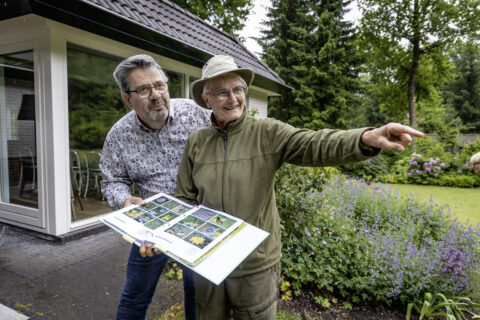 Een bewoner en Tuinranger in een tuin kijken naar een plant