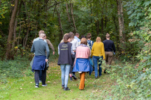 Een groep mensen wandelt samen over een bosrijk pad.