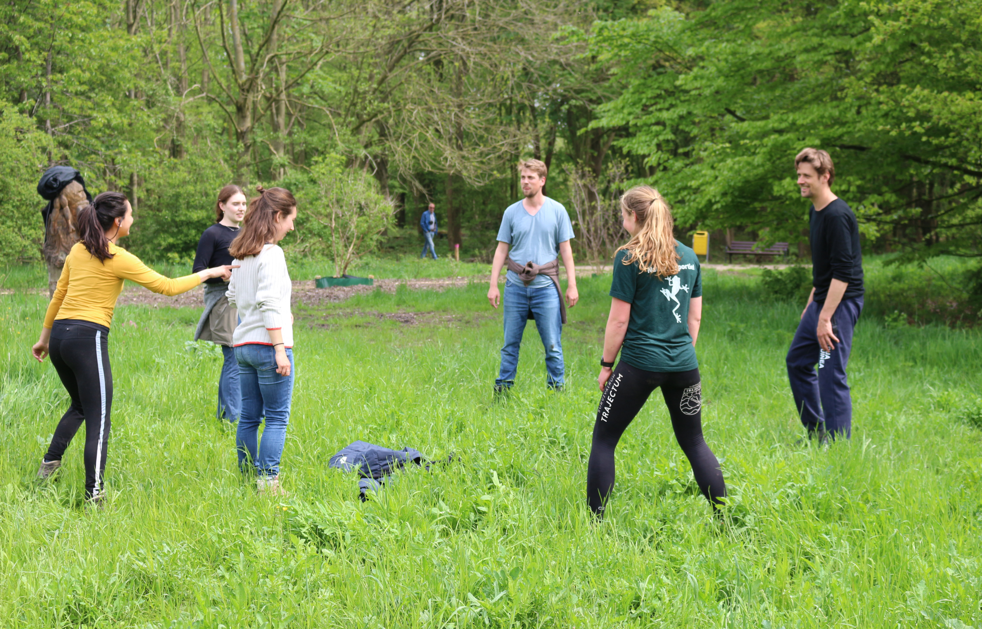 Een groep mensen speelt een spel in een groene weide in het bos.