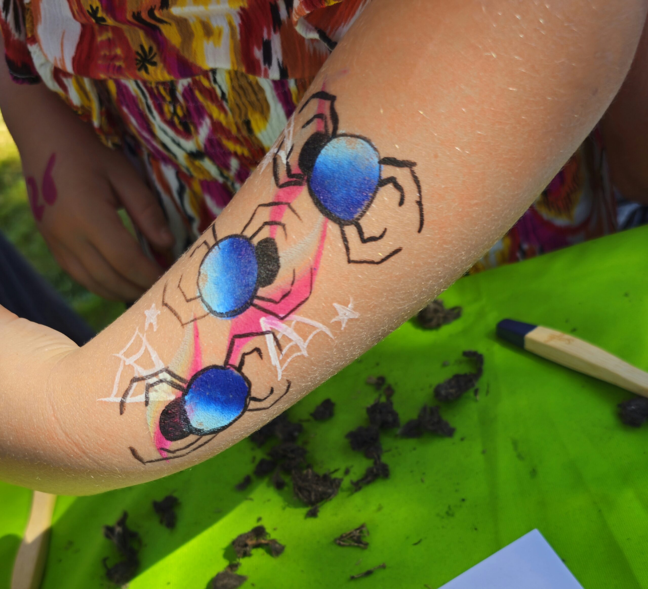 Arm met blauwe spinnen en spinnenwebben geschilderd op huid. Kind in kleurrijke kleding.