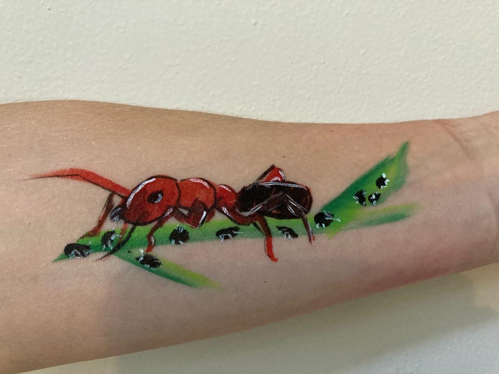 Een kleurrijke tekening van een rode mier op een arm, met groene bladeren op de achtergrond.