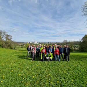 Een groep mensen poseert samen op een grasveld onder een heldere hemel.