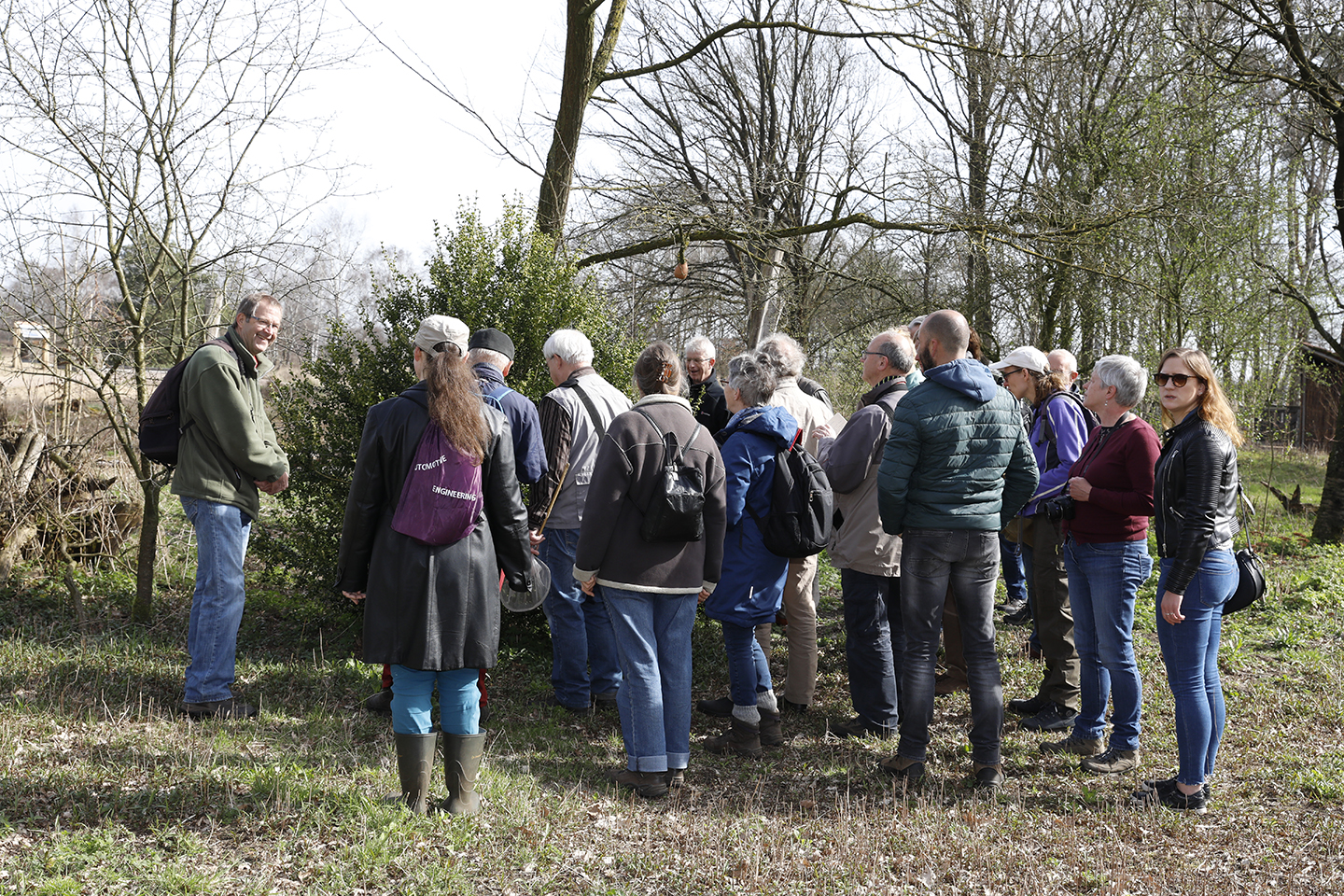 Een groep mensen observeert de natuur tijdens een wandeling in een bosrijke omgeving.