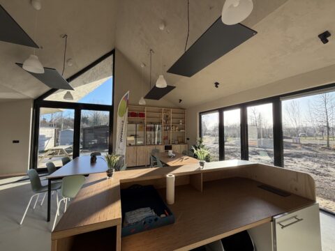 Interieur van een lichte moderne ruimte met houten meubels en grote ramen met uitzicht op bomen.