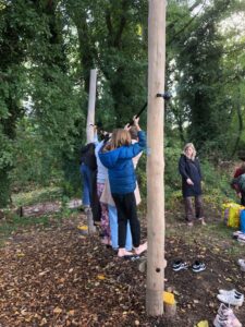 Tieners balanceren op een rijtje planken in het bos, schoenen liggen op de grond.