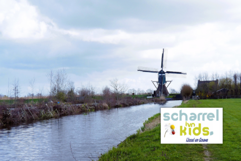Windmolen langs een kanaal onder bewolkte hemel met het logo van ScharrelKids links onderin.