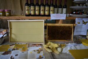 Bijenraatdisplay met honingraten, honingpotten en flessen wijn op een houten tafel.
