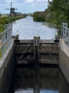 Sluisje bij een vaart met op de achtergrond een molen