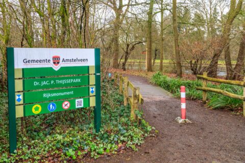 Toegang tot Dr. Jac. P. Thijssepark in Amstelveen met bord en pad omringd door bomen.