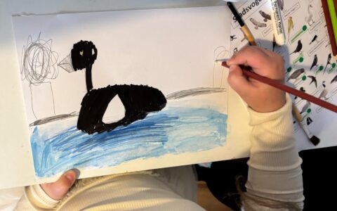 Kind dat een tekening maakt van een eend in het water