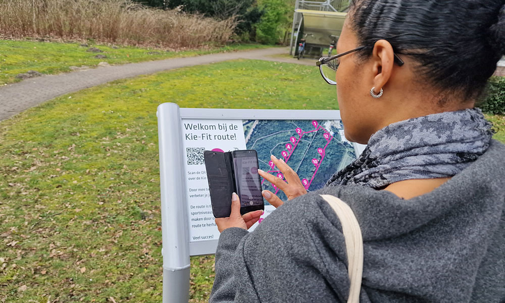 Scannen van QR-code op het informatiebord van Kie-fit route, GGZ inGeest