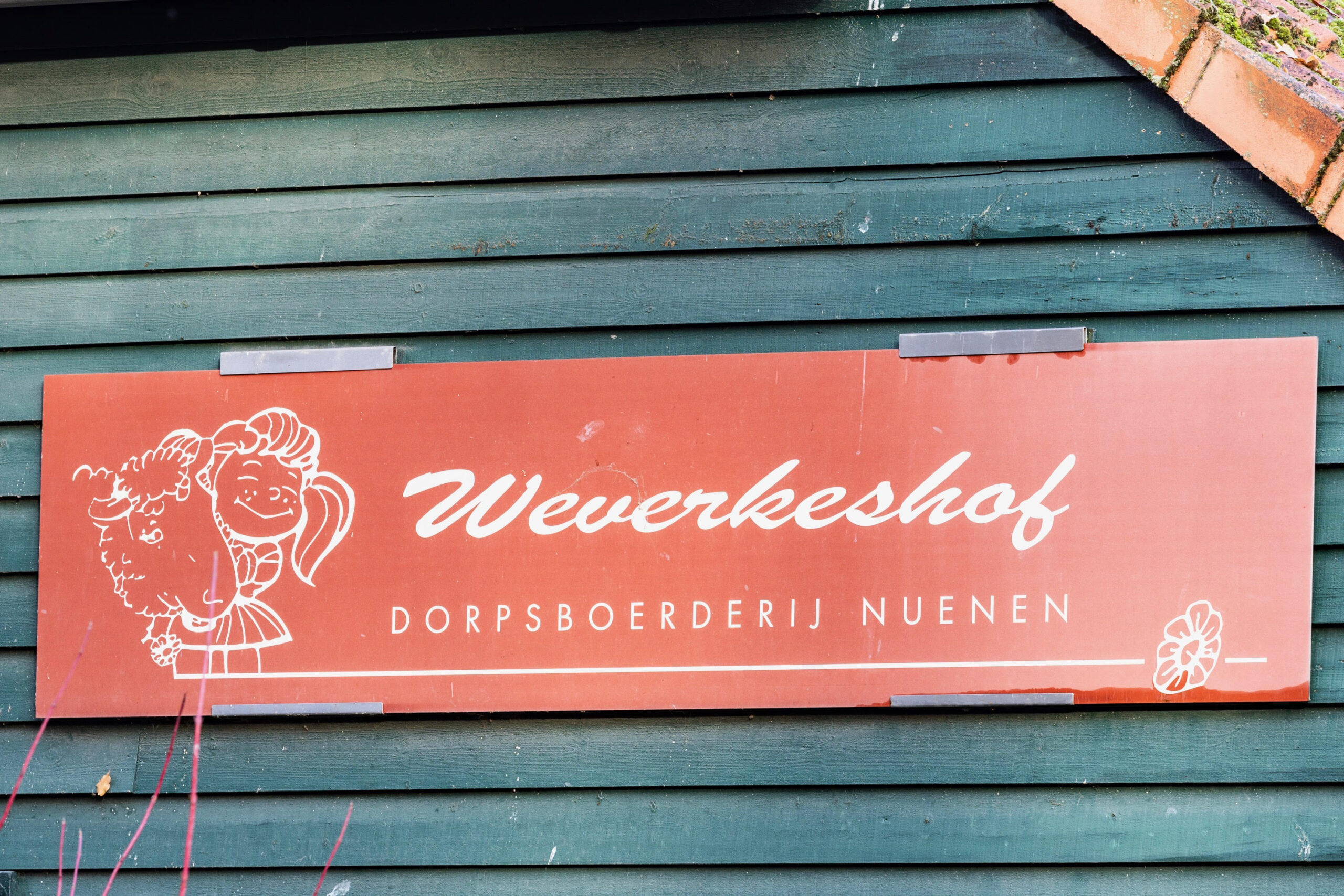 Bruin bord met tekst: "Weverkeshof, Dorpsboerderij Nuenen," en een tekening van een boerderijfiguur.