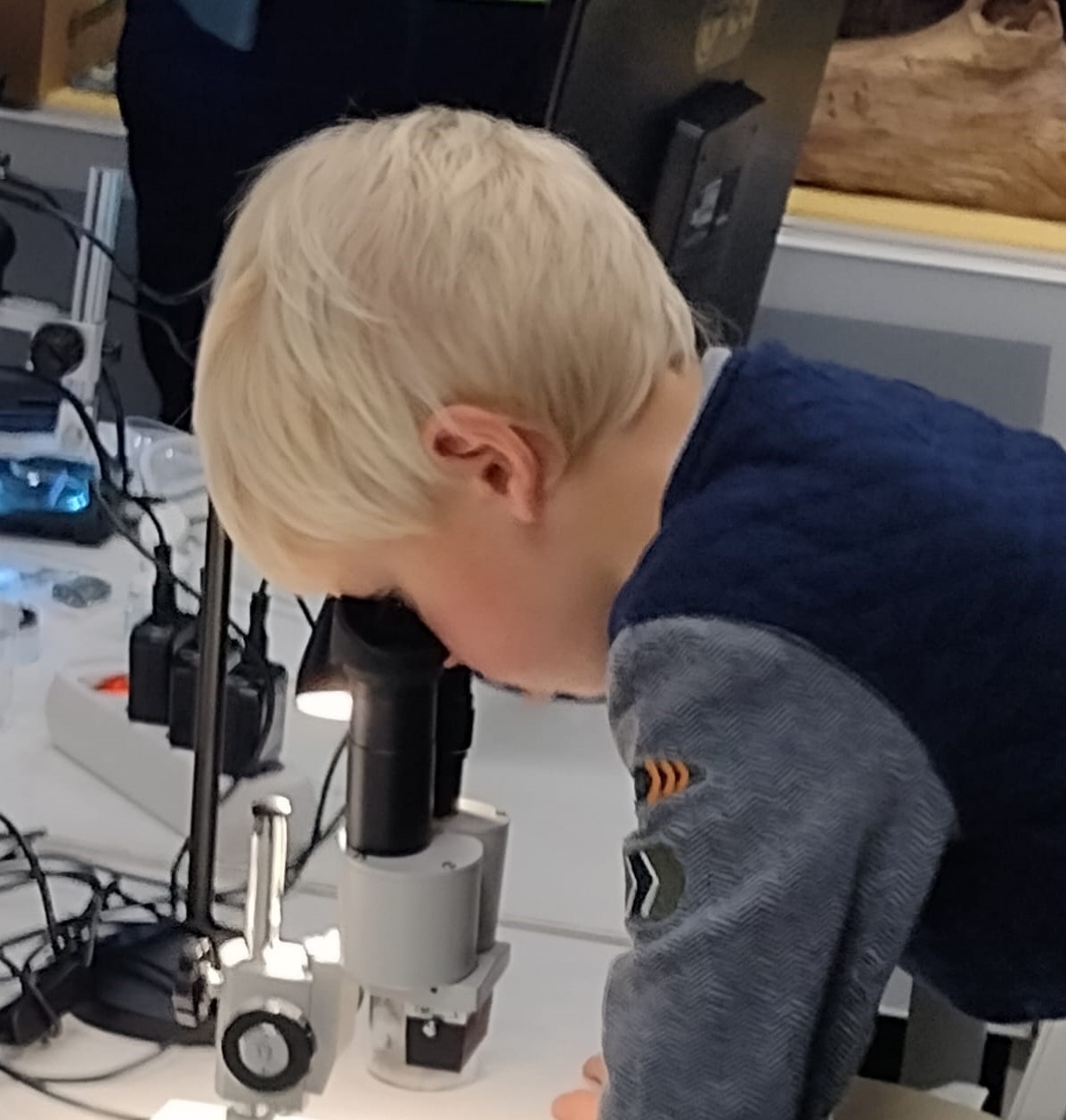 Kind kijkt door een microscoop in een laboratoriumomgeving.