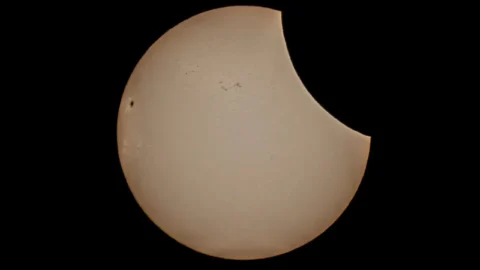 Zonsverduistering met de maan die een hap uit de rechterkant van de zon neemt, op zwarte achtergrond.