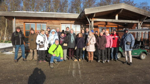Groep mensen in winterkleding poseert voor een houten gebouw met bord "Ontvangstgebouw Eygelshof".