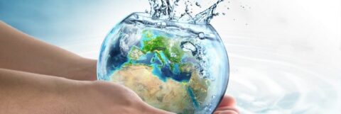 Handen houden een vissenkom met aarde erin, waar water uitspat.