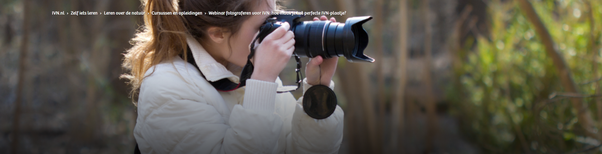 Vrouw met camera richt zich op de natuur, omgeven door bomen en groen.