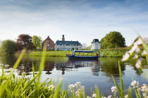 Boot op rivier met kasteel op de achtergrond en bloemen op de voorgrond.