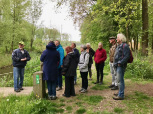 Groepswandeling in het bos met gids, omgeven door bomen en groen.