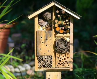 Insectenhotel met diverse natuurlijke materialen in een groene tuinomgeving.
