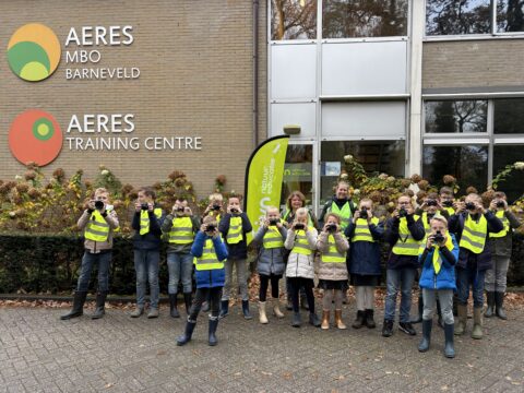 Groep kinderen met camera's en gele hesjes voor Aeres MBO Barneveld.