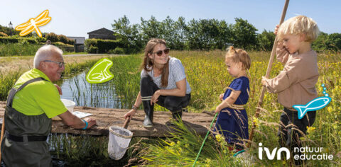 Volwassenen en kinderen onderzoeken een vijver in een veld, met dierenillustraties.