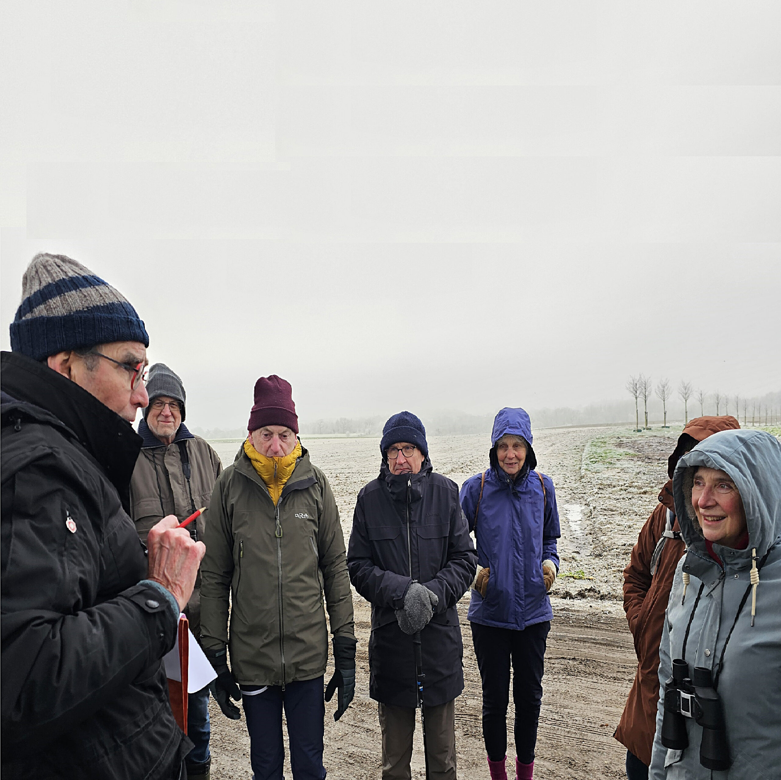 Een groep mensen in winterkleding op een koud, mistig veld.