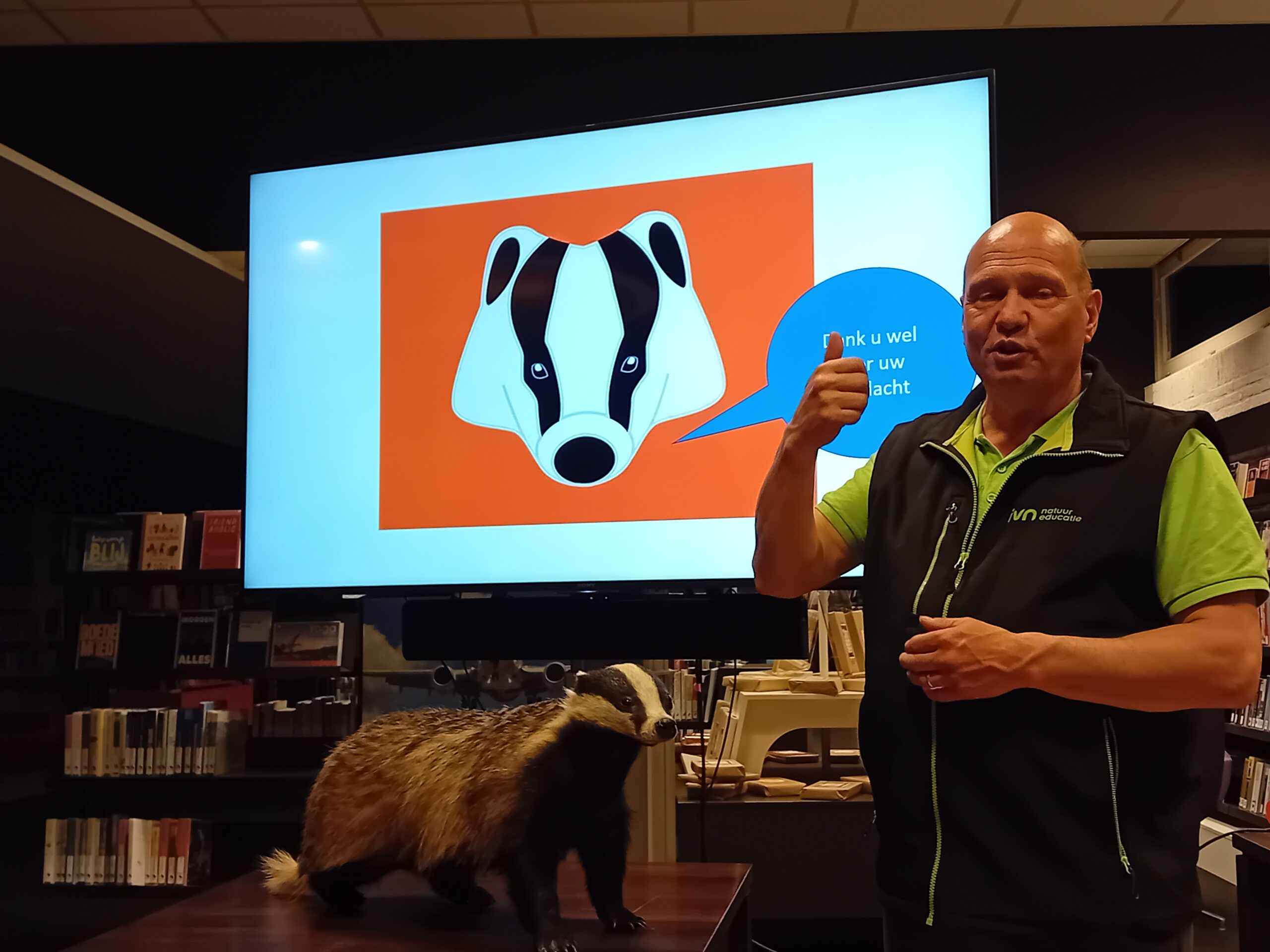 Man bij een opgezette das geeft duim omhoog, scherm toont das-tekening.