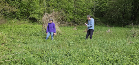 Twee mensen in een groene, grasrijke omgeving met bomen op de achtergrond.