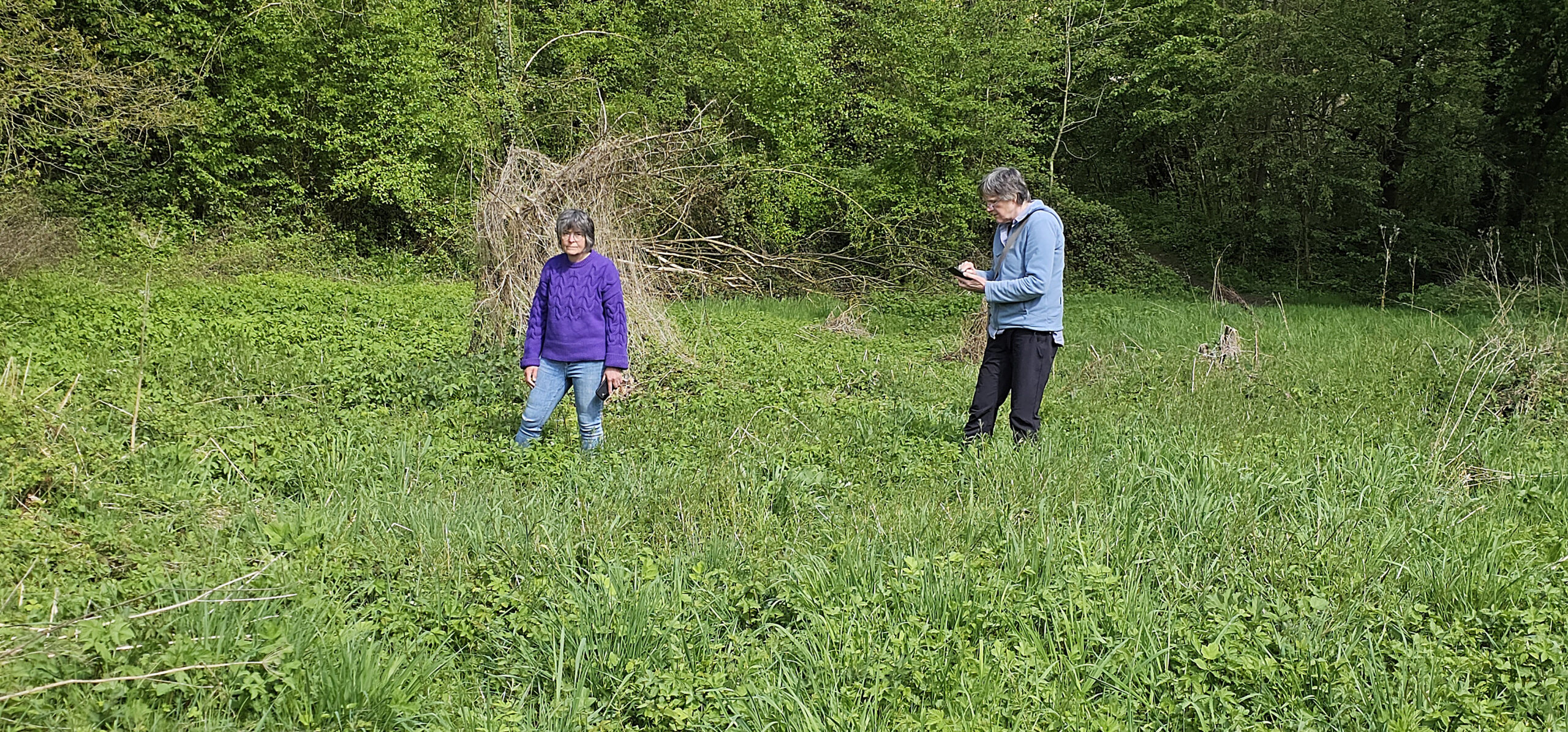 Twee mensen in een groene, grasrijke omgeving met bomen op de achtergrond.