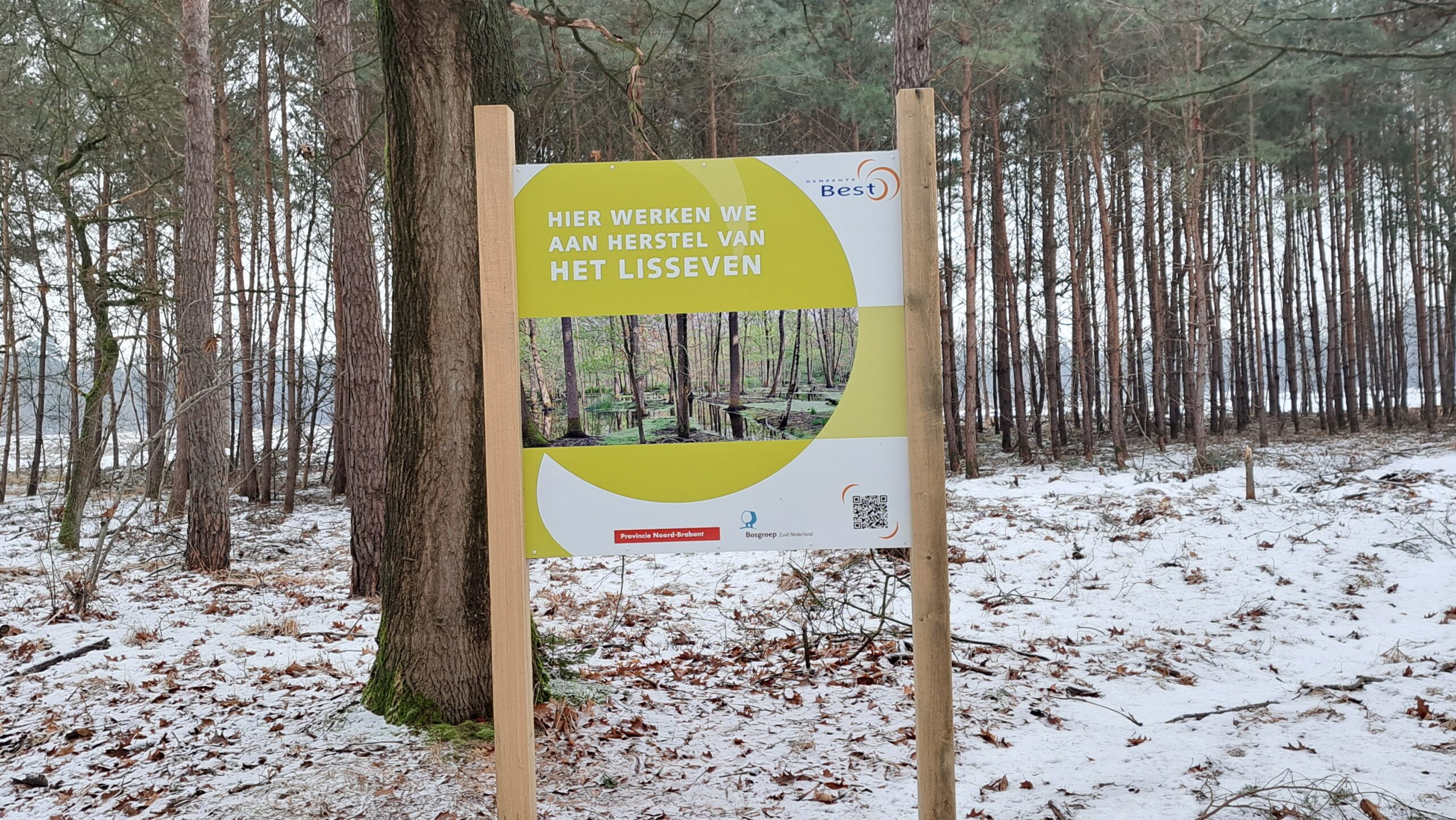 Een bord in een besneeuwd bos, over herstelproject Lisseven.