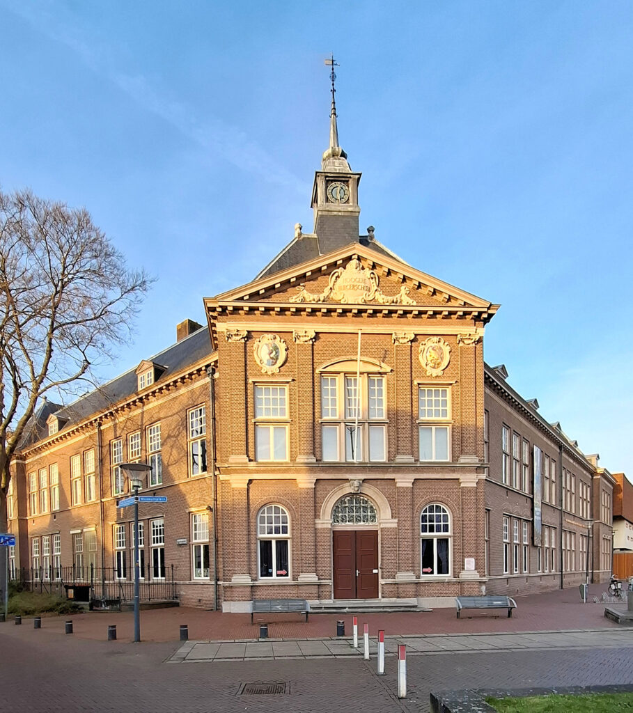 Oud gebouw met kloktoren en sierlijke gevel op een zonnige dag.