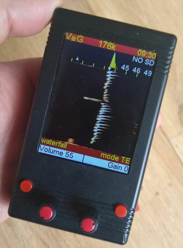 Hand houdt een draagbaar elektronisch apparaat met een scherm dat geluidsgolven weergeeft.