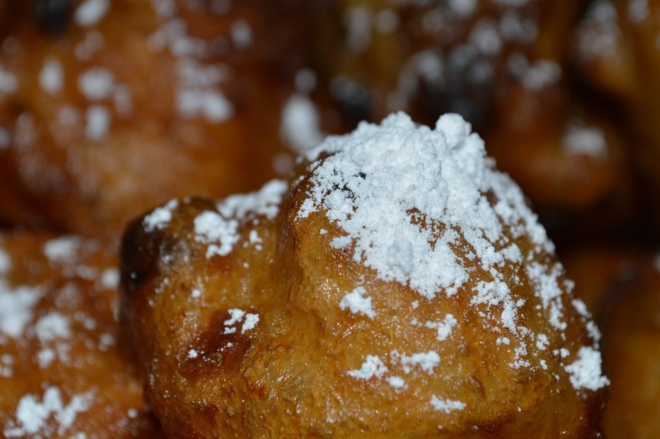 Close-up van een oliebol met poedersuiker erop.