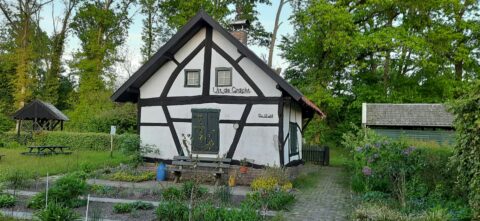 Oude vakwerkboerderij in groene tuin, met zitgedeelte en omliggende natuur.
