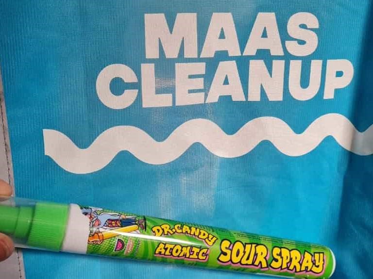 Blauwe tas met "MAAS CLEANUP" tekst, groene zure spray vooraan.