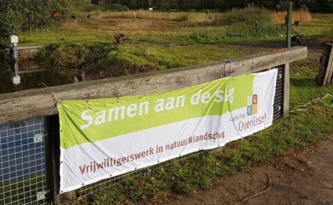 Banner met "Samen aan de slag", in natuurgebied voor vrijwilligerswerk, Landschap Overijssel.