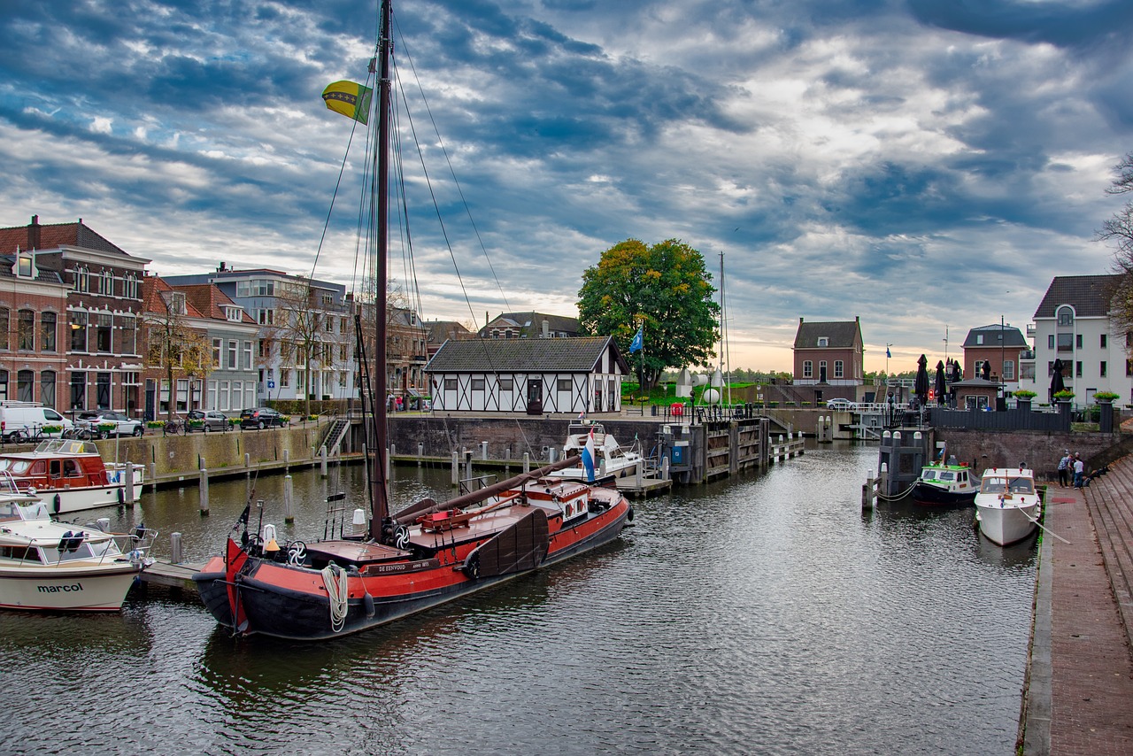 Historische haven met boten, huizen aan kade, onder bewolkte lucht.