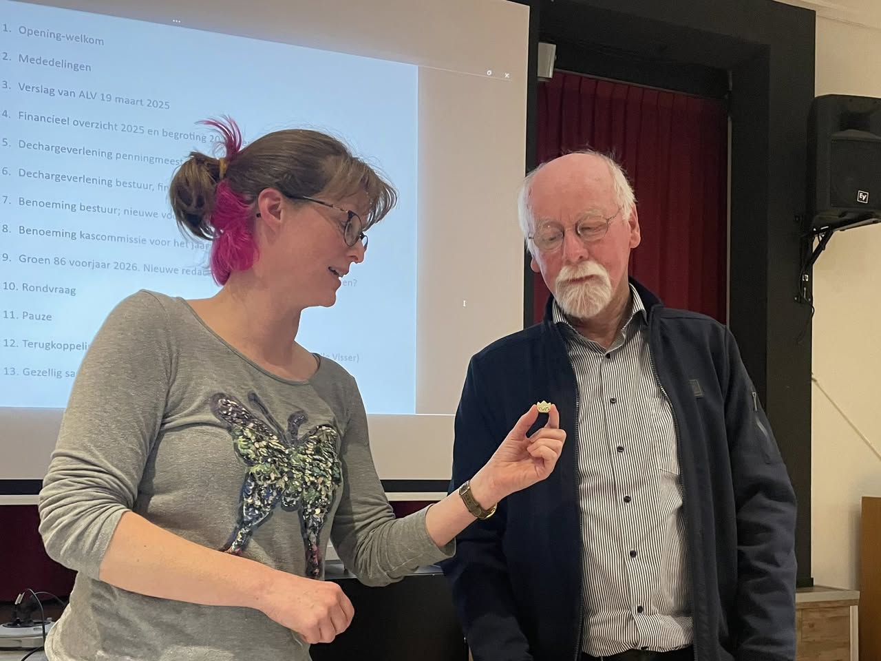 Twee mensen praten voor een projectiescherm met vergaderagenda.