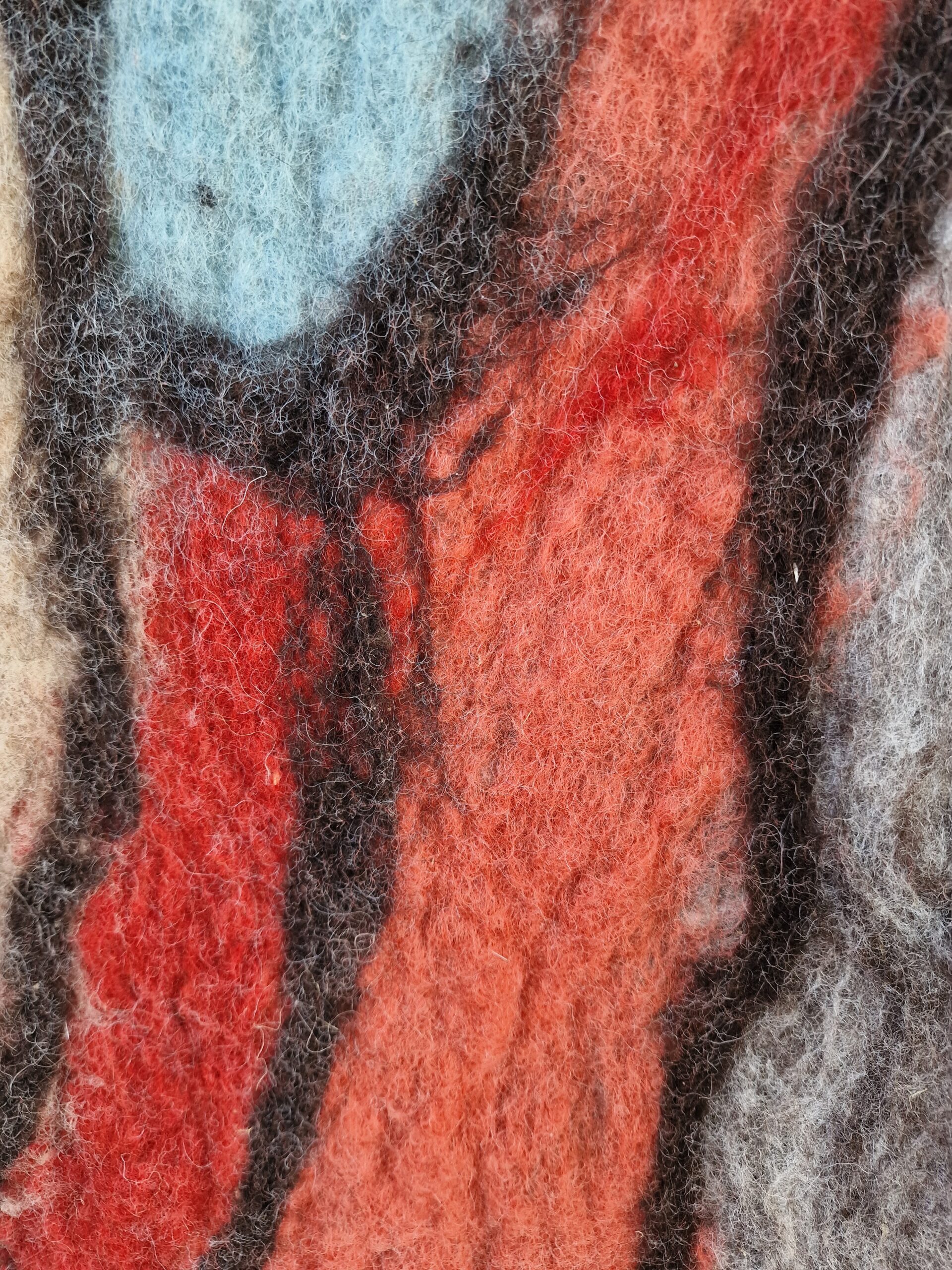 Vilttextuur met rode, blauwe en grijze tinten en zwarte lijnen.