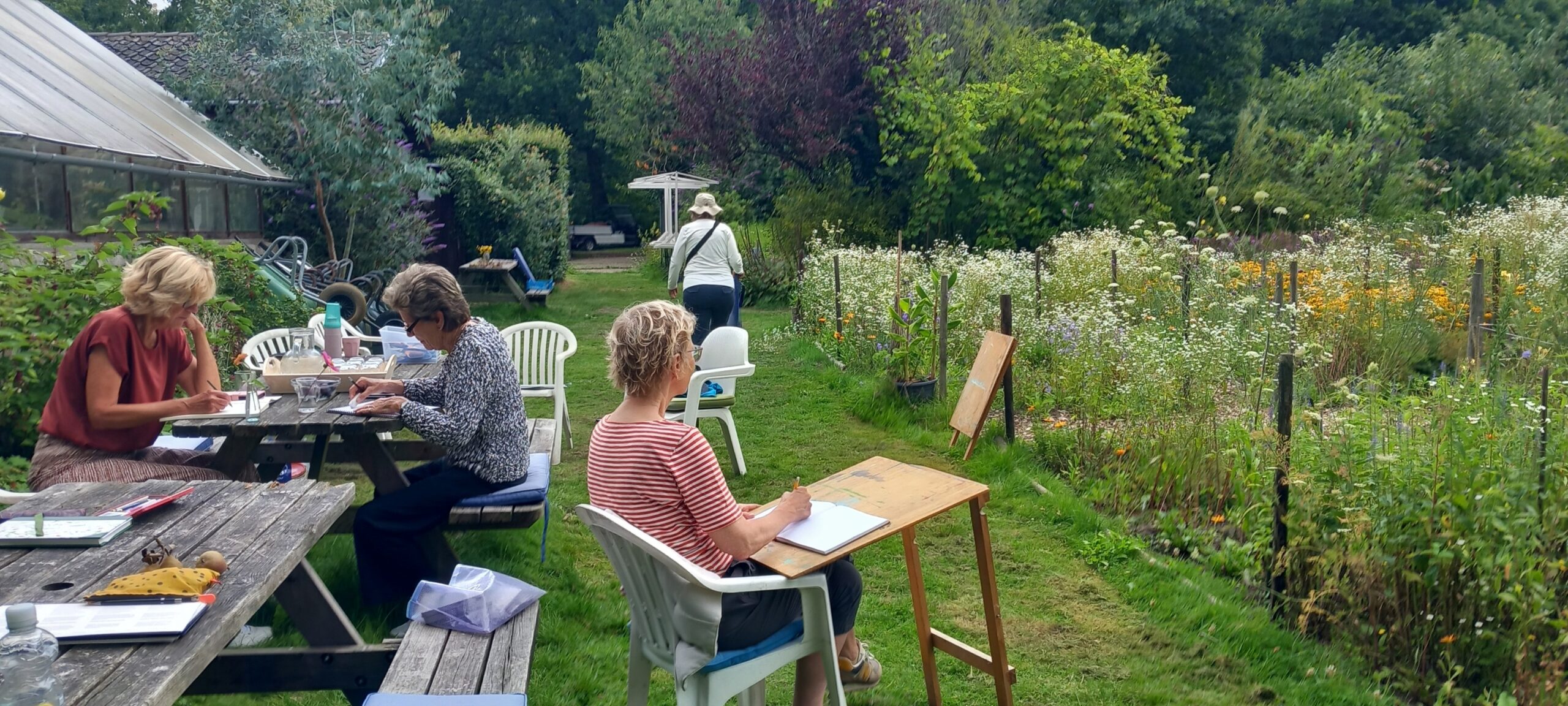 Mensen schetsen in een tuin met bloemen, zitplaatsen en een kas.