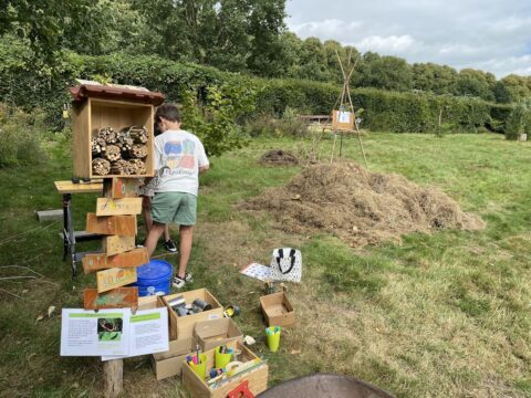 Kind werkt aan een insectenhotel in een natuurgebied met materialen en informatiepanelen.