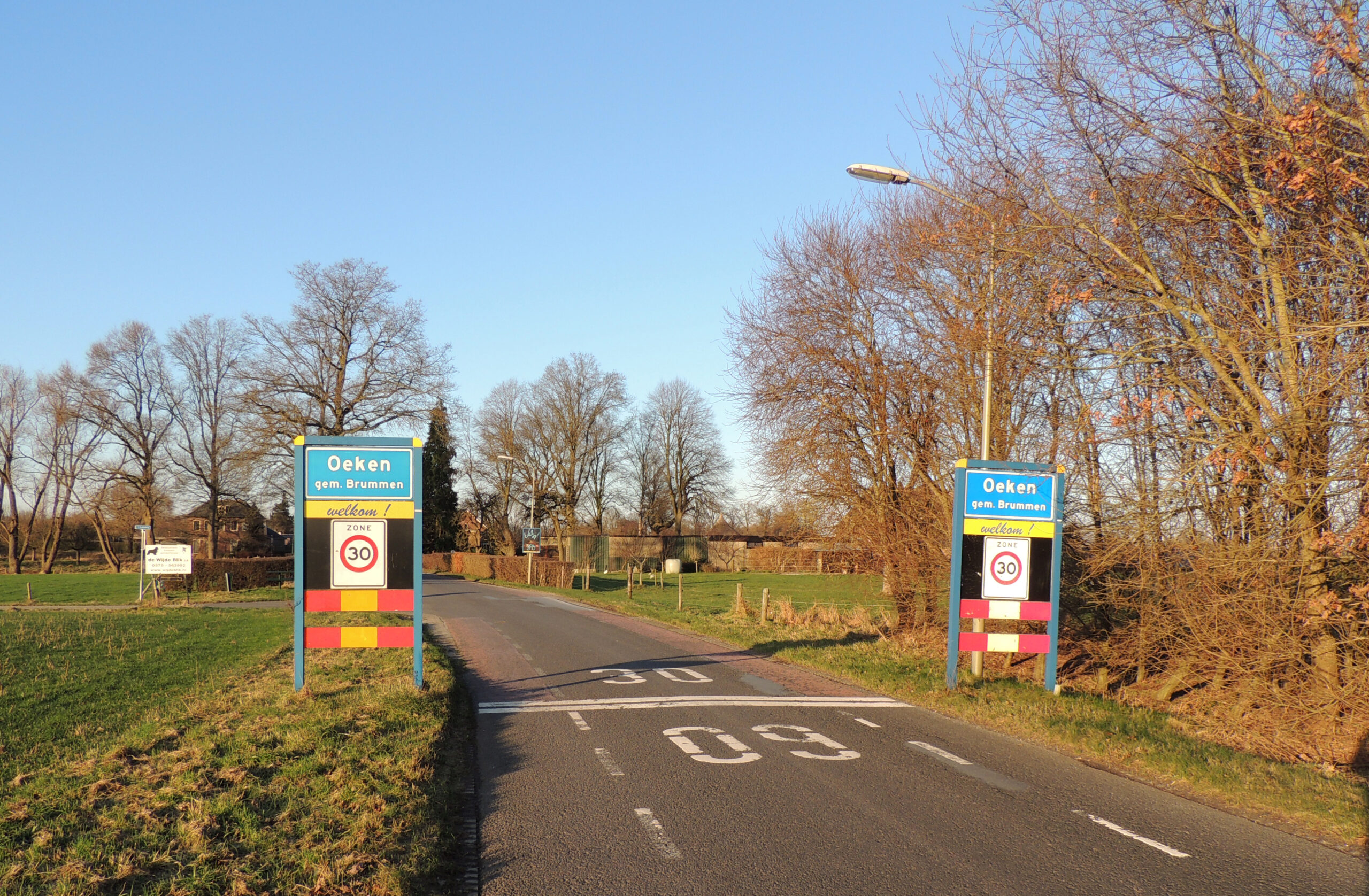 Ingang van Oeken, Brummen, met snelheidslimiet van 30 km/u en omliggende bomen.