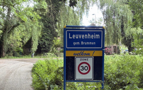 Blauw welkomsbord Leuvenheim met 30 km/u zone, omgeven door groen en bomen.