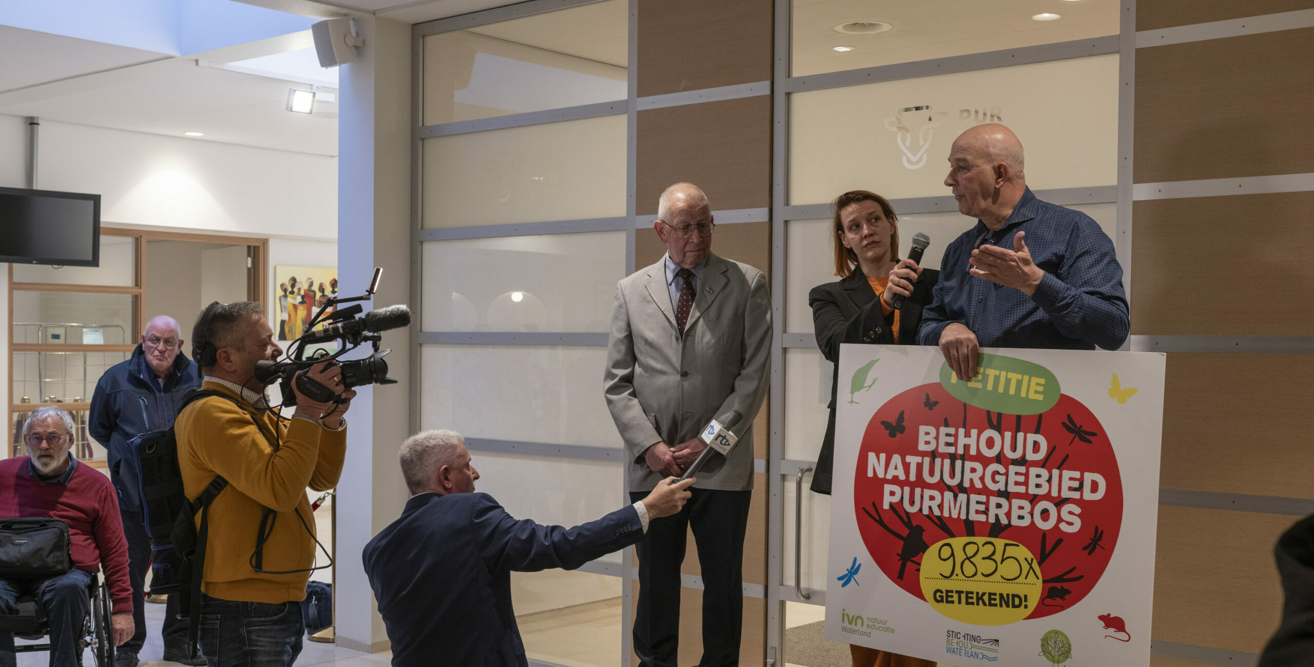 Mensen presenteren een petitie voor behoud van Purmerbos, ondersteund door 9835 handtekeningen.